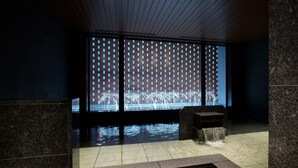 A modern indoor space with a water feature, a brick wall with a geometric pattern, and a tiled floor.