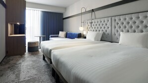 A hotel room with a large bed, a bedside table, a chair, a wardrobe, and a window with curtains.
