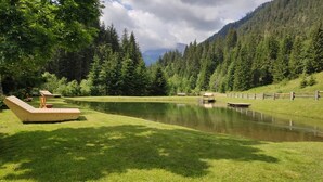 Un tranquillo scenario con vista lago, una terrazza in legno e poltrone relax.