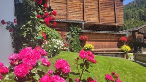 Una baita in legno con un giardino curato, ricco di rose rosa vivaci e altri fiori vari.