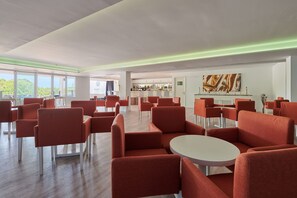A spacious lounge area with red chairs and a bar in the background. - Aluasoul Hotel Carolina (Capdepera)