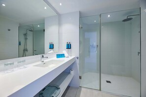 A modern bathroom with a glass-enclosed shower, a large mirror, and a white vanity with two sinks. - Aluasoul Hotel Carolina (Capdepera)