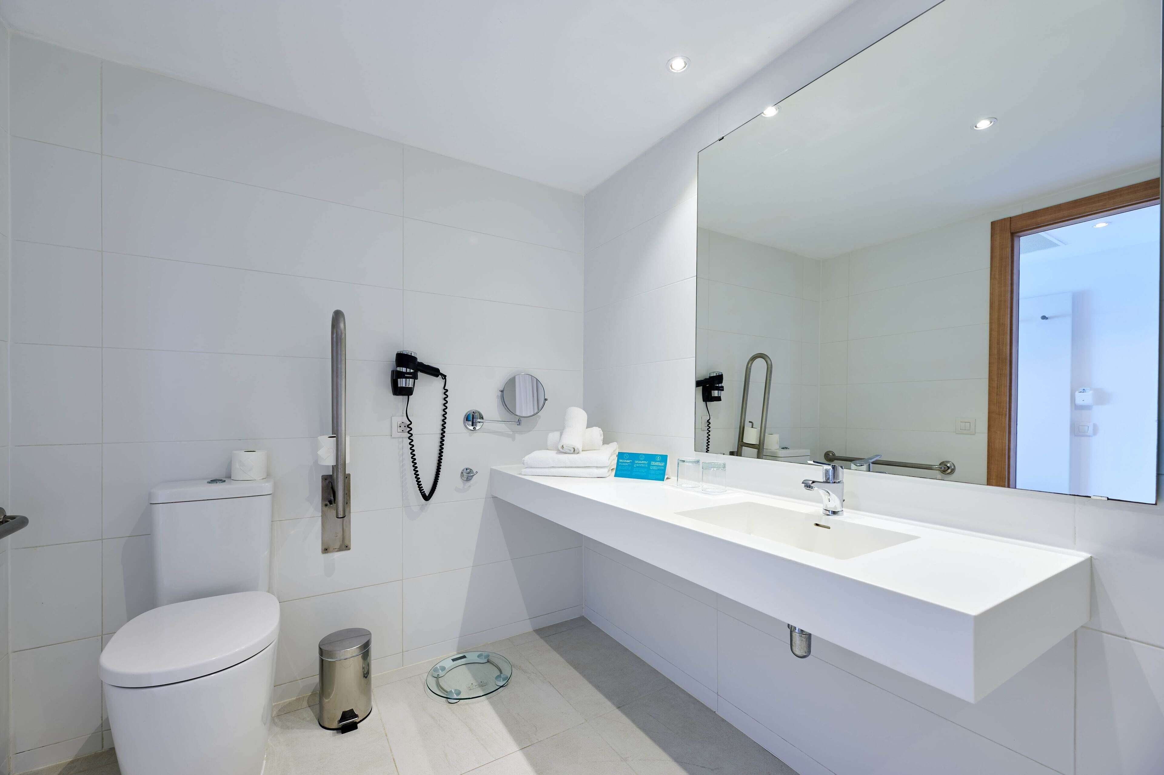 Un baño moderno con un lavabo, espejo y váter blancos.