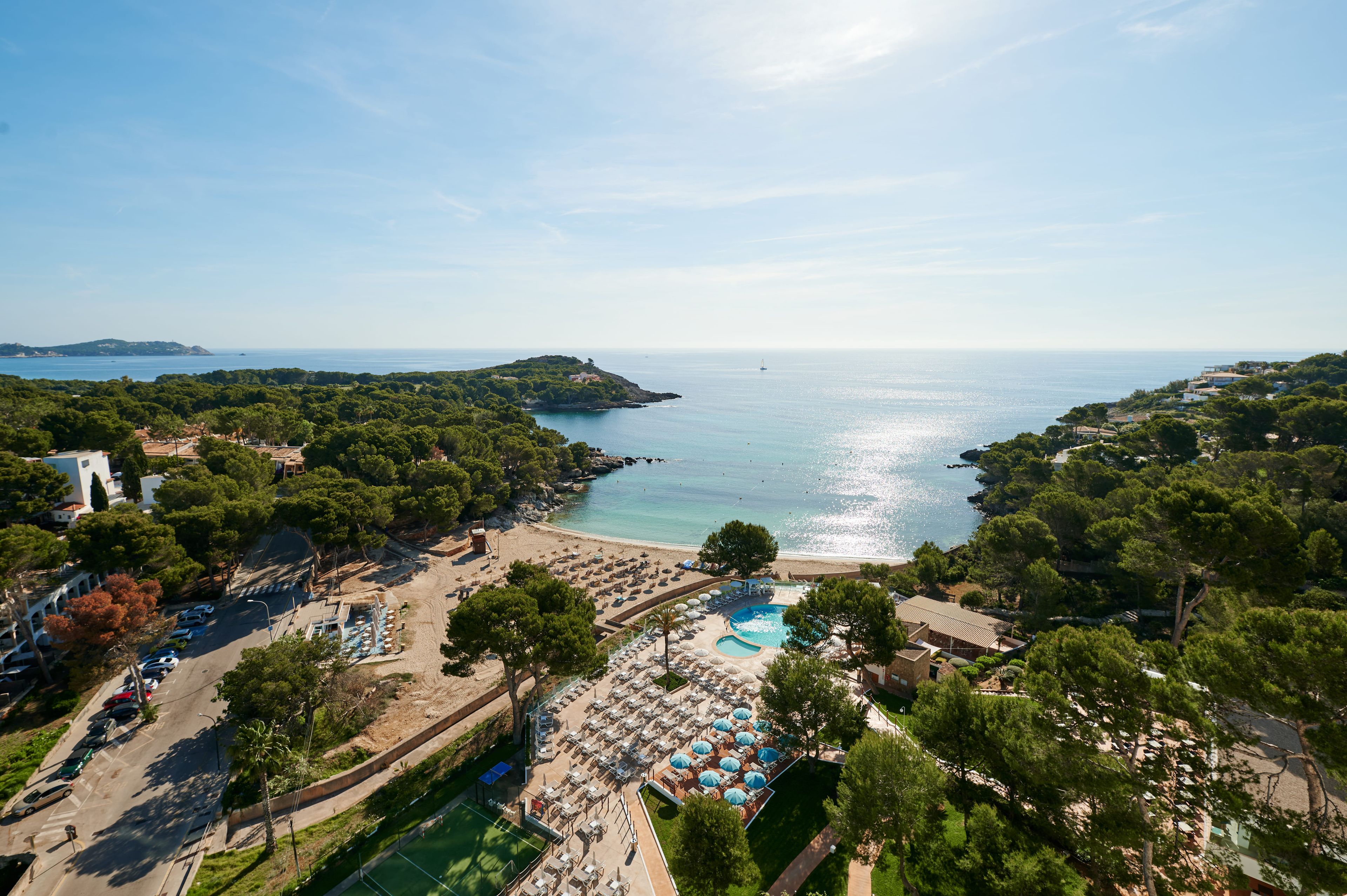 Vue aérienne d’une station balnéaire avec une piscine, une plage et une végétation luxuriante.