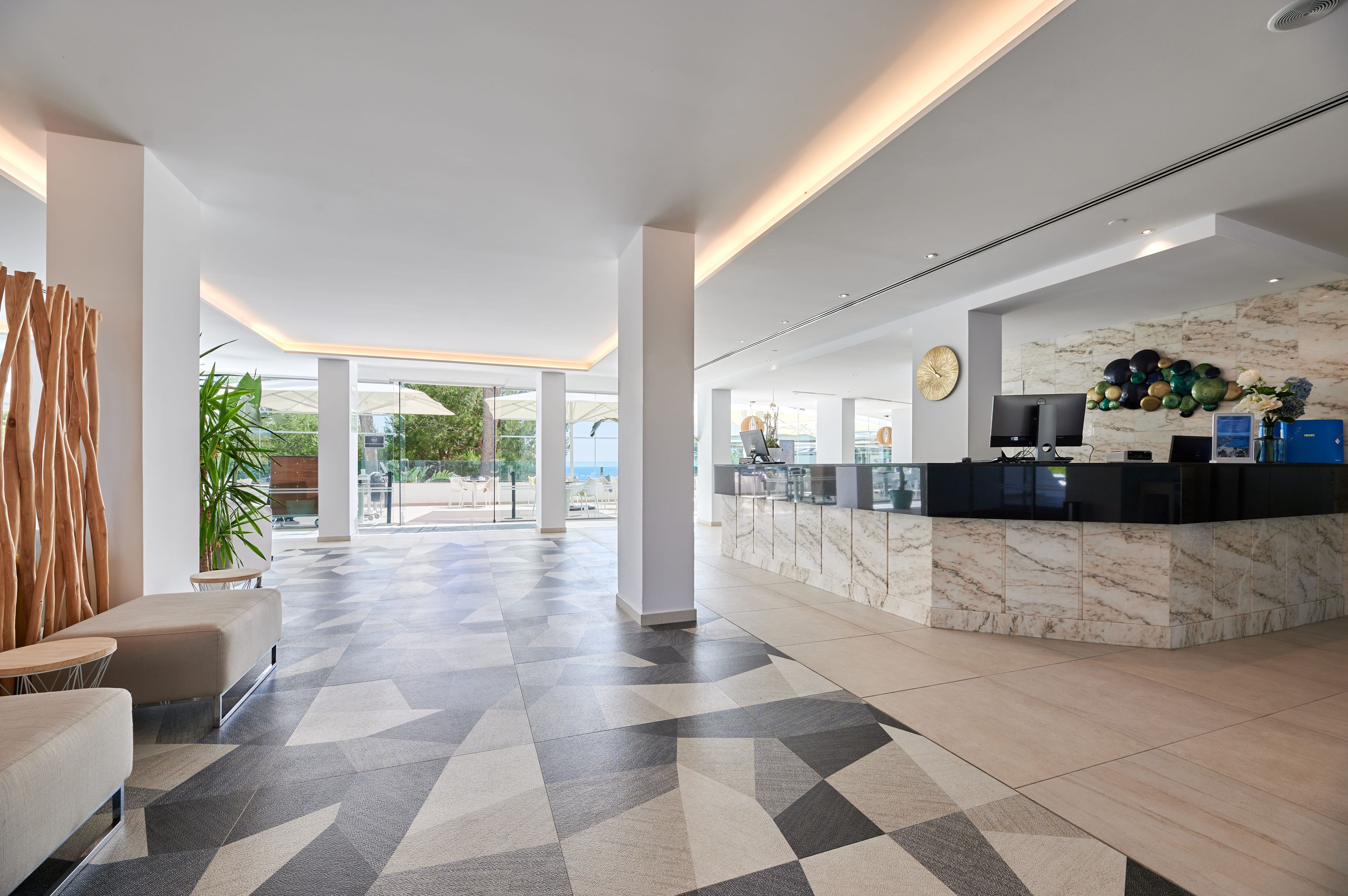 Una hall moderna con reception, area salotto e vista sull'esterno.