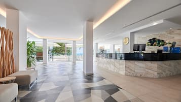 Een moderne lobby met een receptiebalie, een zithoek en uitzicht op de omgeving.