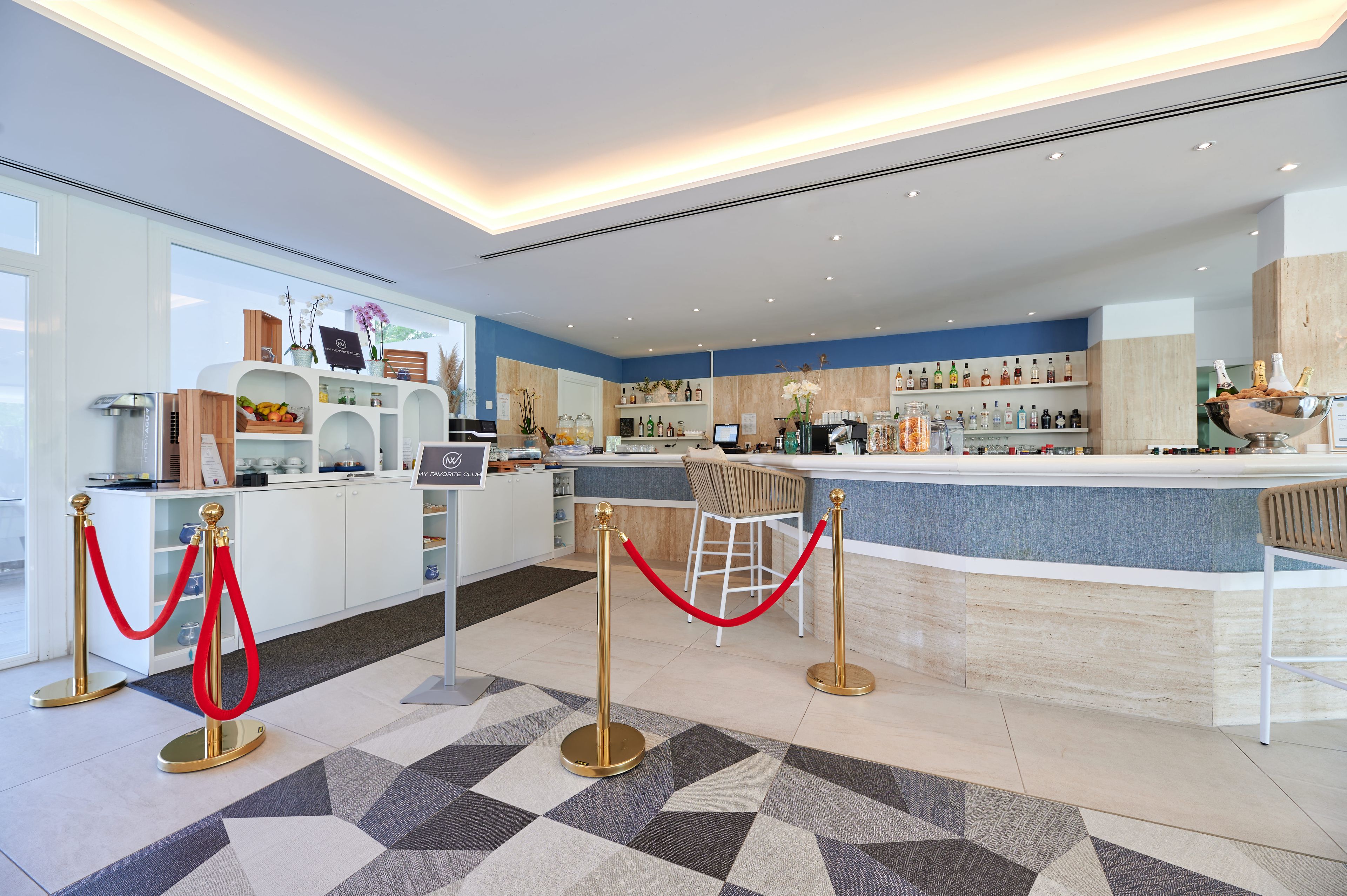 A modern hotel lobby with a reception desk, bar area, and a seating area.
