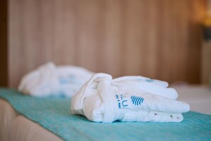 A neatly folded white towel with blue text on a teal-colored bedspread. - Aluasoul Hotel Carolina (Capdepera)