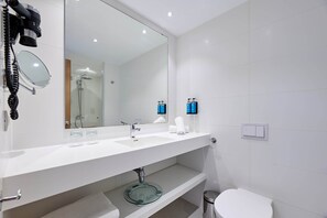 A modern bathroom with a white sink, a large mirror, and a glass shower enclosure. - Aluasoul Hotel Carolina (Capdepera)