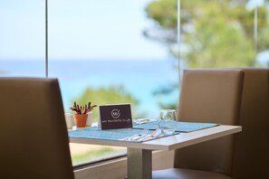 A table with a placemat, a laptop, a nameplate, a glass of water, and a potted plant. - Aluasoul Hotel Carolina (Capdepera)