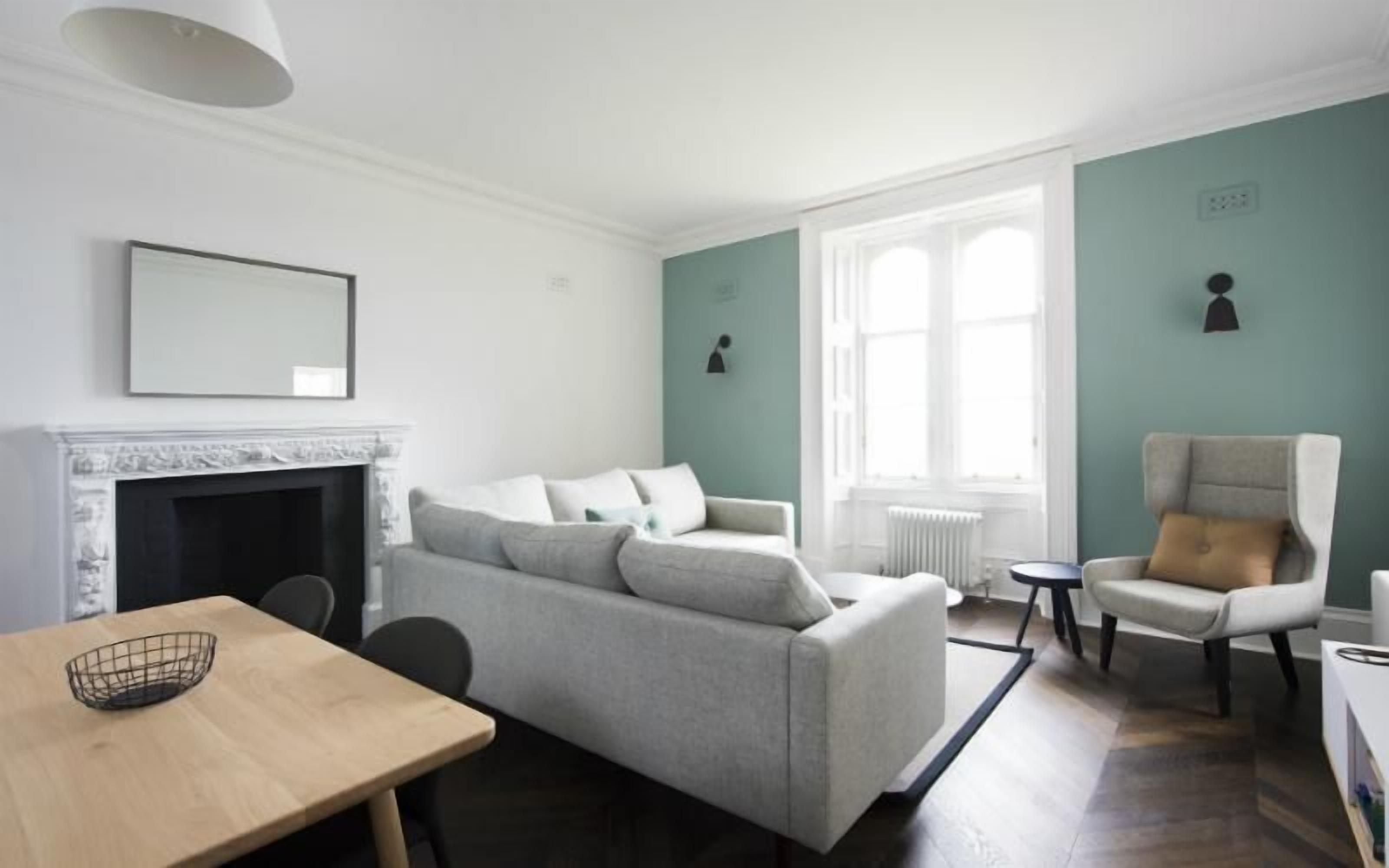 Een moderne woonkamer met een open haard, een bank, een eettafel en een stoel.