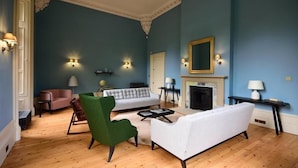 A living room with a blue wall, a fireplace, and a green armchair. - A lews castle that sleeps 4 guests  in 2 bedrooms (Isle of Lewis)