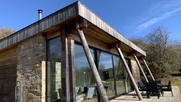 Une maison moderne dotée de grandes fenêtres en verre et d’une terrasse en bois.