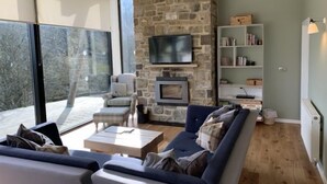 Un salon moderne avec un mur en pierre, une cheminée, un canapé et un téléviseur.