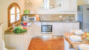 Eine Küche mit weißen Schränken, einer Mikrowelle, einem Backofen und einem Spülbecken.
