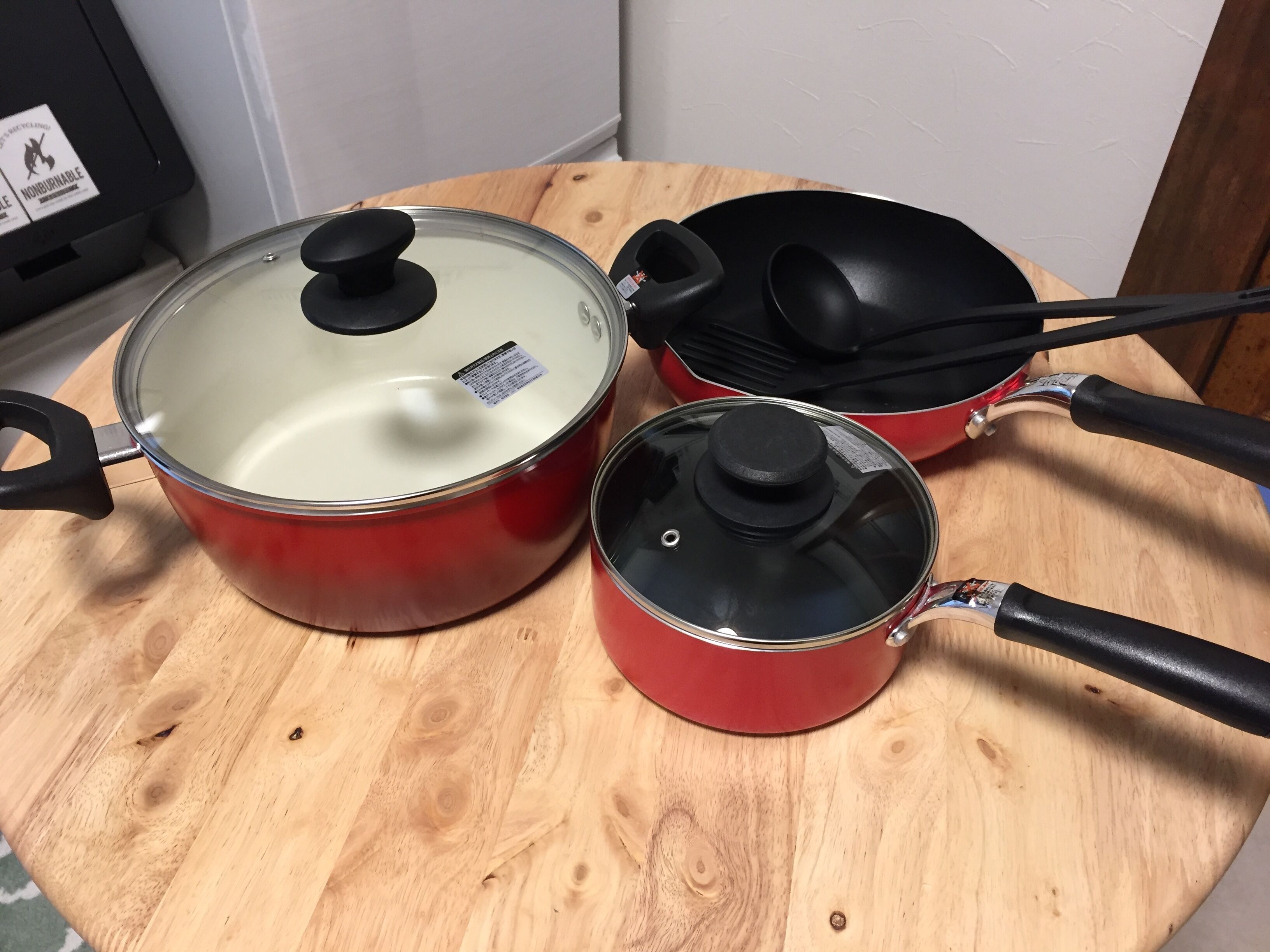 Three red pots with lids on a wooden table.