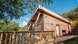 Une cabane en bois avec un toit en pente, une terrasse et un espace clôturé.