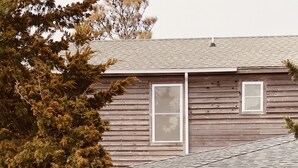 Ein Holzhaus mit Veranda, einer kleinen Terrasse und einem Fenster.