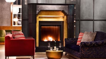 A cozy living room with a fireplace, red and blue sofas, and a round coffee table.
