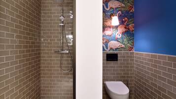 Un baño con ducha, inodoro y una pared con un mural floral.