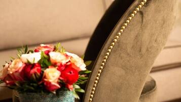 A close-up of a chair with a gold bead trim and a vase with flowers.