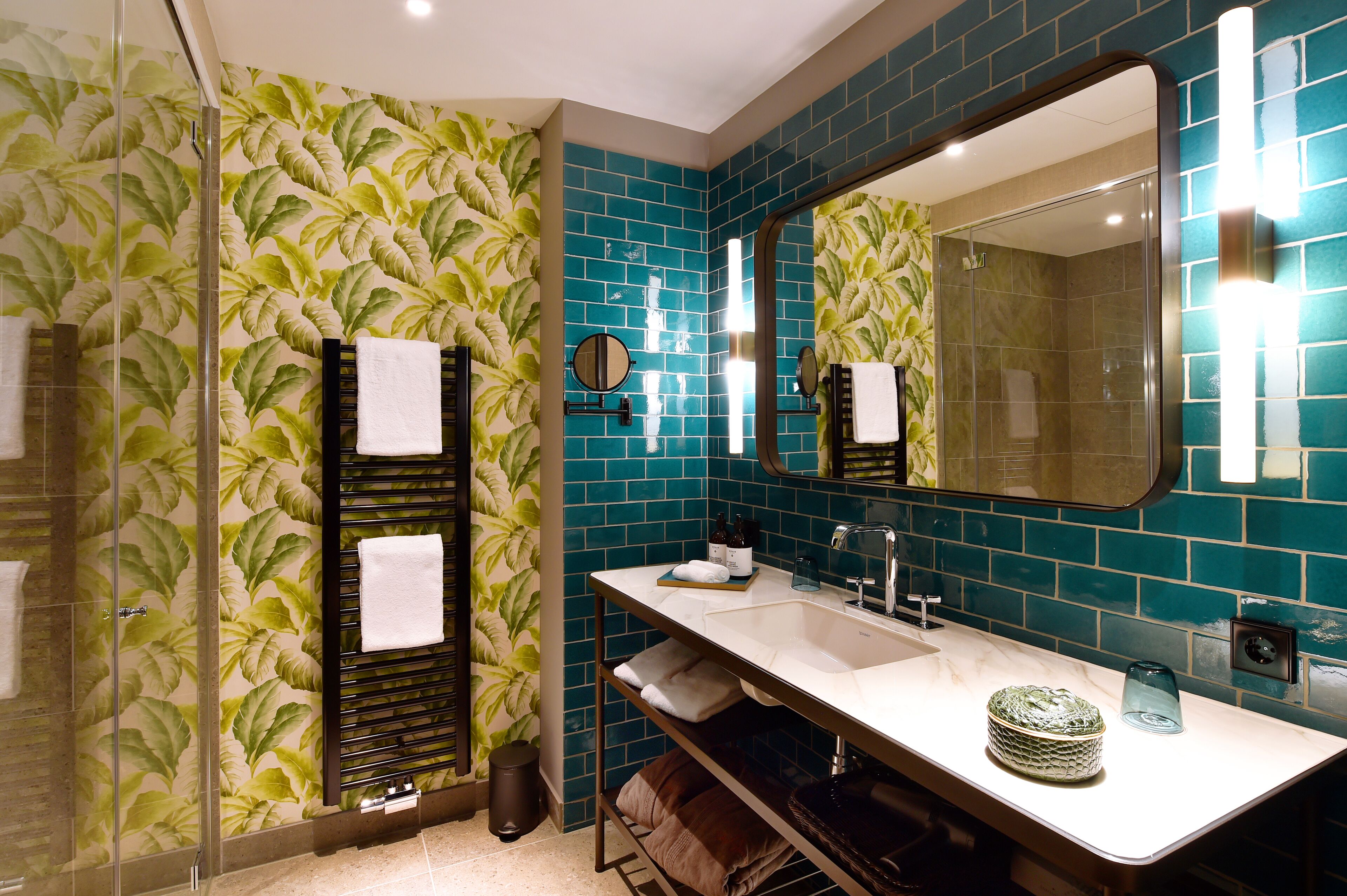 Un baño con un espejo grande, lavamanos y zona de ducha.