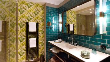 Un baño con un espejo grande, lavamanos y zona de ducha.