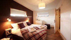Ein Schlafzimmer mit Bett, Nachttisch, Lampe und einem Spiegel an der Wand.