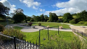 A park with a swing set, a pond, and a walking path.