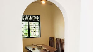 Un coin repas avec une table ronde, des chaises et une fenêtre ornée de barreaux décoratifs.