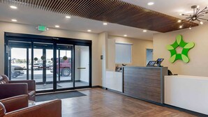 A reception area with a modern design, featuring a reception desk, seating area, and a large glass door leading outside. - Extended Stay America Premier Suites Savannah Pooler (Pooler)