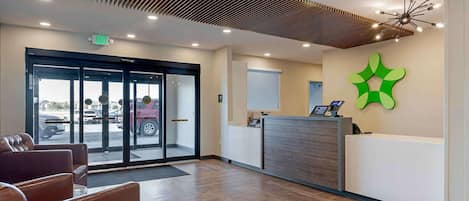 A reception area with a modern design, featuring a reception desk, seating area, and a large glass door leading outside.