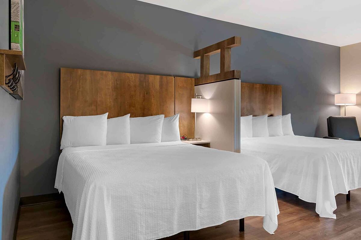 A hotel room with two beds, wooden headboards, and bedside lamps.