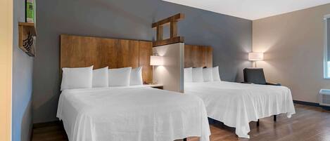 A hotel room with two beds, wooden headboards, and bedside lamps.