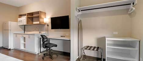 A modern kitchen with a built-in microwave, a flat-screen TV, and a small dining table.