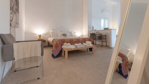 A modern bedroom with a bed, bedside tables, a chair, and a desk. - Kinanto Bioresort (Ispica)