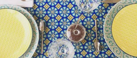 A table set with plates, bowls, glasses, and cutlery on a patterned tablecloth.