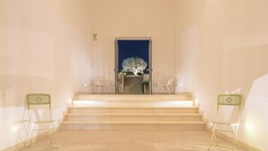A staircase leading to a balcony with a tree, two green chairs, and a sign on the wall. - Kinanto Bioresort (Ispica)