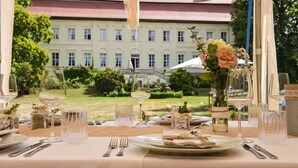 Tavola imbandita per un pasto con vista su un edificio e un giardino.