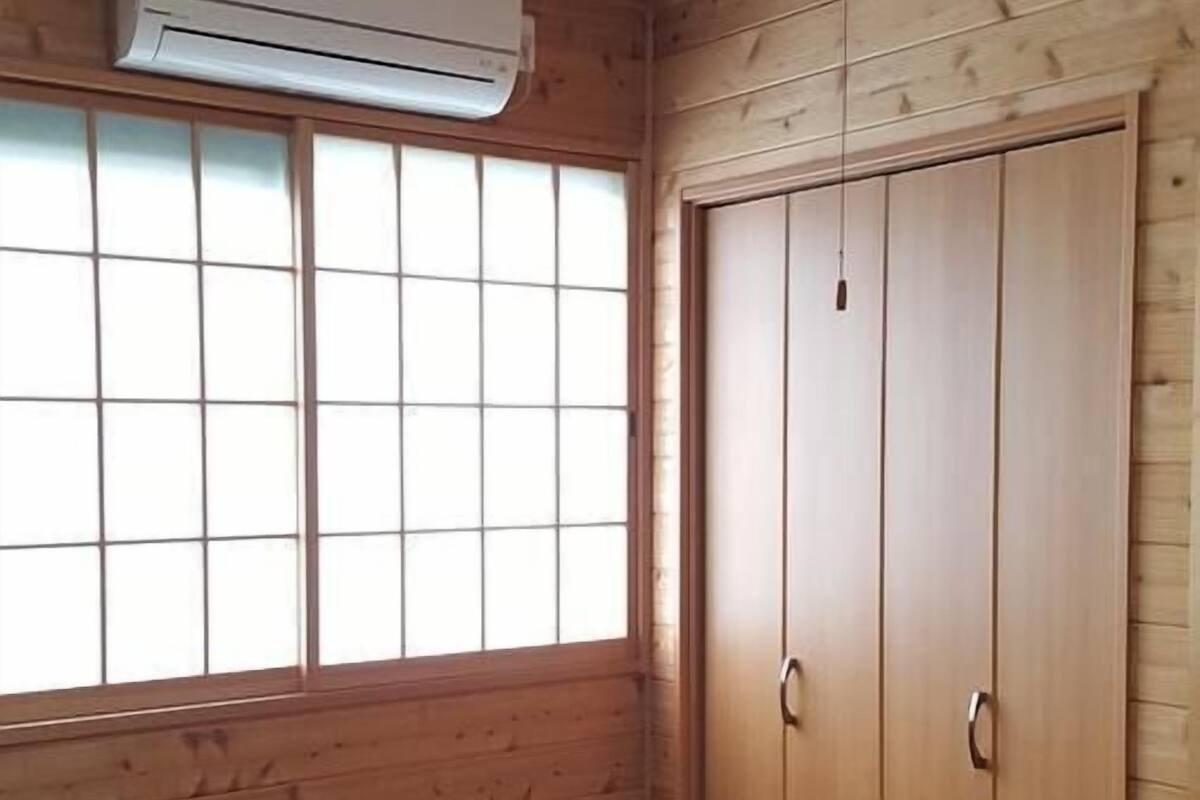 Habitació amb parets de fusta, sòl de tatami i una porta corredissa, i aire condicionat fixat al sostre.