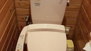 Ein kleines Badezimmer mit Holzvertäfelung, einer Toilette, einem Bidet und einem Toilettenpapierhalter.