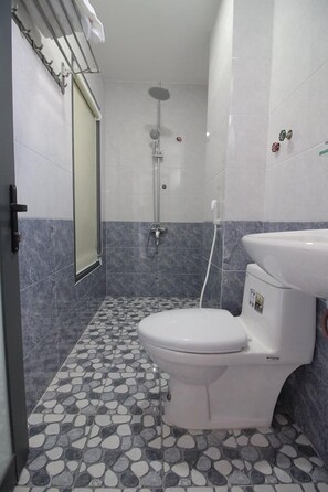 A bathroom with a toilet, a shower, and a sink. - Phu Xuan Hotel (Quy Nhon Nam)