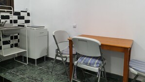 A small kitchenette with a sink, a small refrigerator, and a chair with a striped cushion.