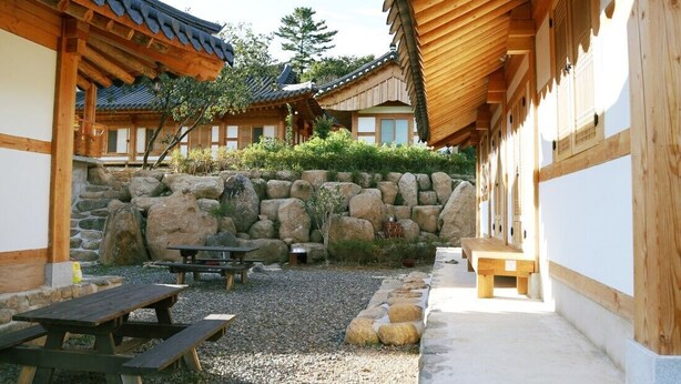 A traditional Korean courtyard with wooden buildings, a stone wall, and a gravel path. - Hadong Today Sun Hanok Traditional House (Hadong)