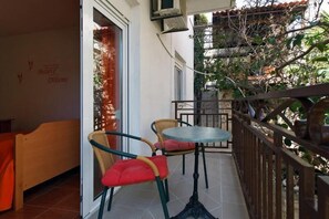 A balcony with a table and chairs, a small garden area, and a wall with a motivational quote. - Nikola Leko Guest House (Hvar)