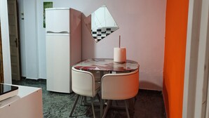 A compact kitchen with a refrigerator, a small dining table with chairs, and a wall-mounted mirror. - Low Cost Room Plaza de Hierro II (San Bartolomé de Tirajana)