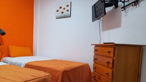 A room with two beds, an orange wall, a wooden dresser, and a flat-screen TV mounted on the wall. - Low Cost Room Plaza de Hierro II (San Bartolomé de Tirajana)