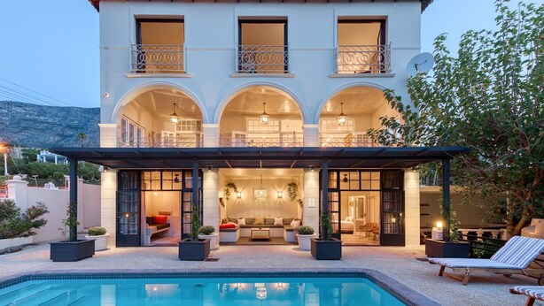 A two-story building with a swimming pool, outdoor seating area, and a covered patio. - De Tafelberg Guesthouse (Cape Town)