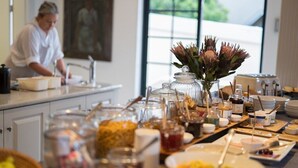 A buffet setup with various food items and beverages, including jars of preserves and a vase with flowers. - De Tafelberg Guesthouse (Cape Town)