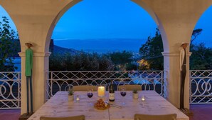 A table set for two with candles, wine glasses, and a bottle of wine, overlooking a scenic view. - De Tafelberg Guesthouse (Cape Town)